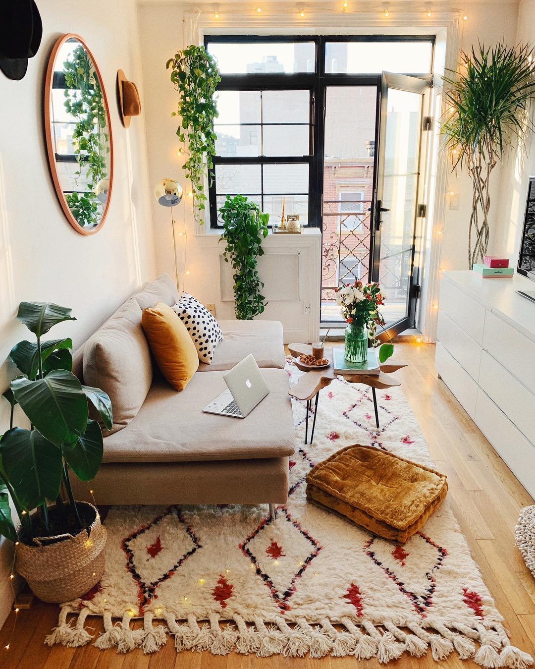 Small apartment living room with plants hanging from ceiling and white patterned rug. Photo by Instagram user @viktoria.dahlberg