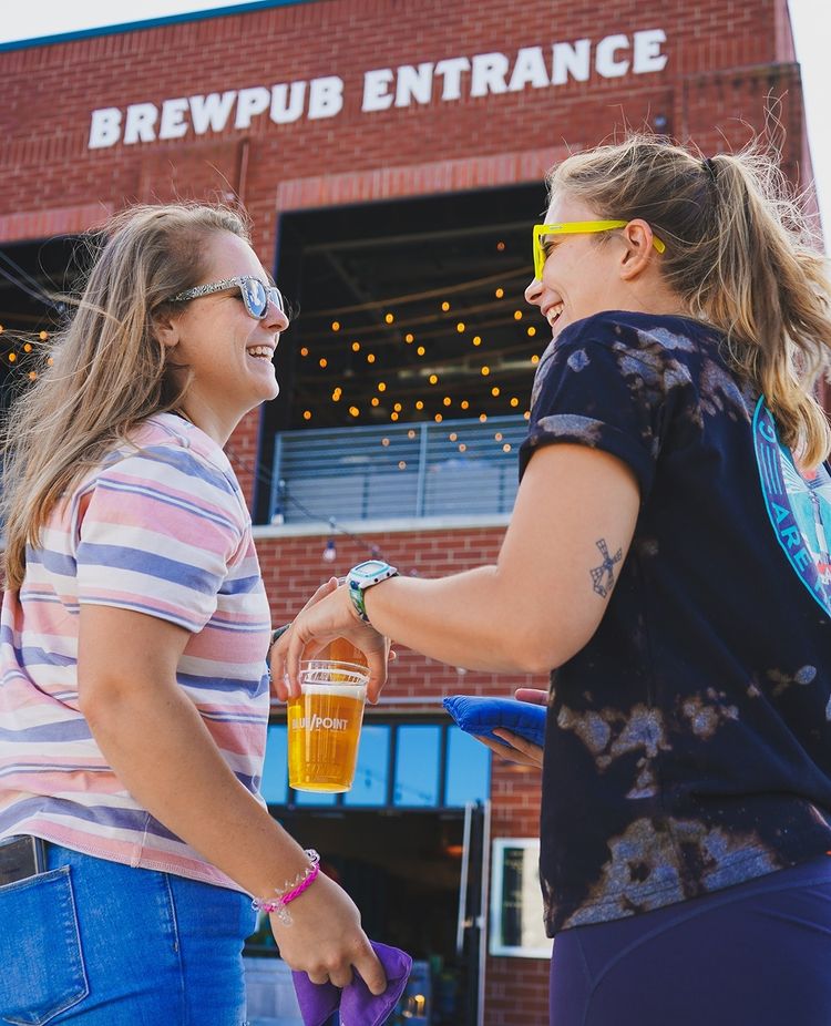 Two women holding a beer at Blue Point Brewpub. Photo by Instagram user @bluepointbrewpub