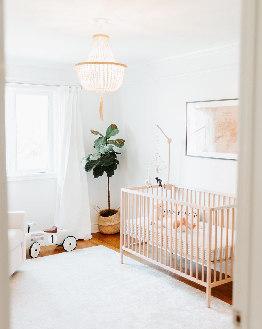 Neutral baby room with chandelier. Photo by Instagram user @laurakelly.co