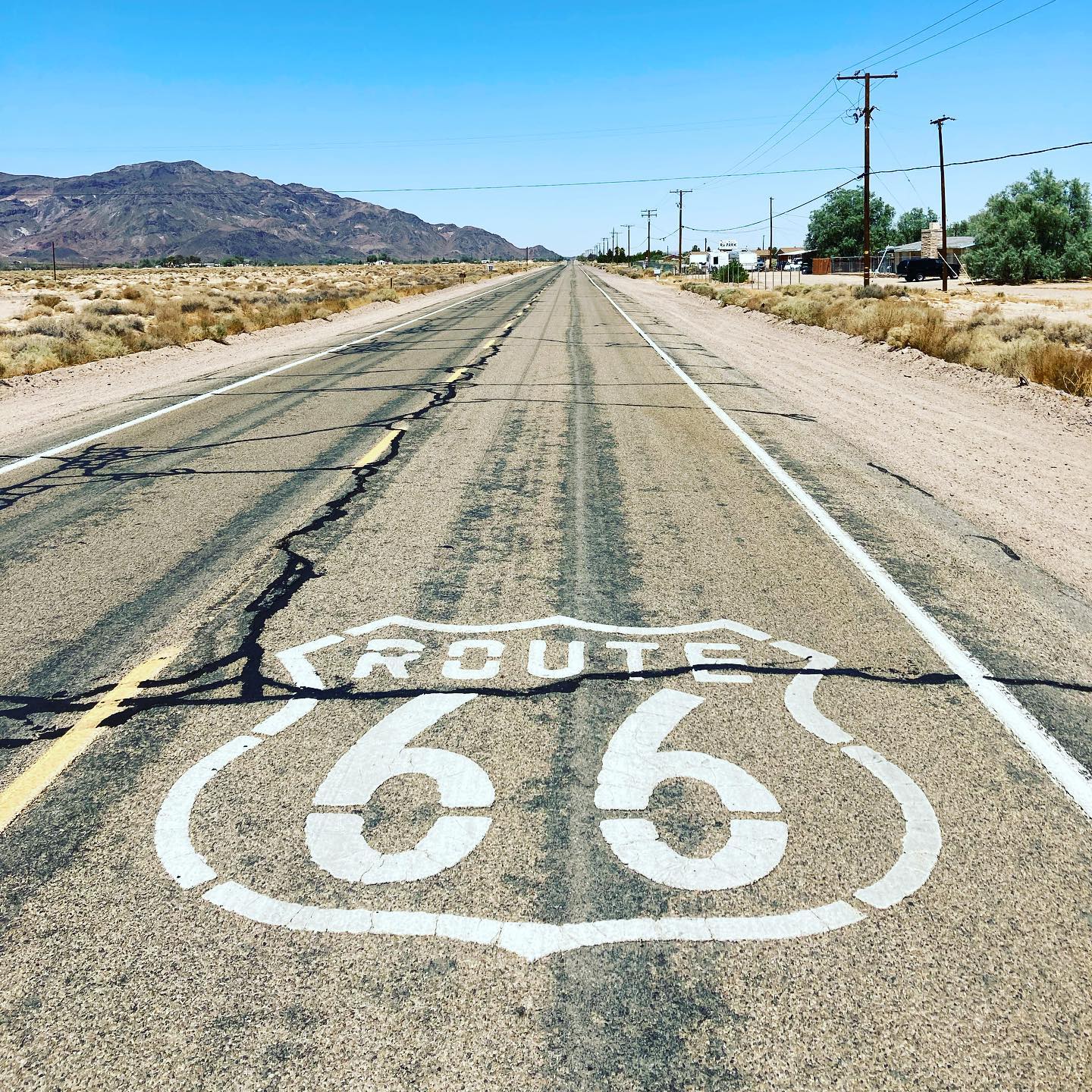 A road stretching into the distant horizon with the Route 66 symbol painted onto it. Photo by Instagram user @townofspectre