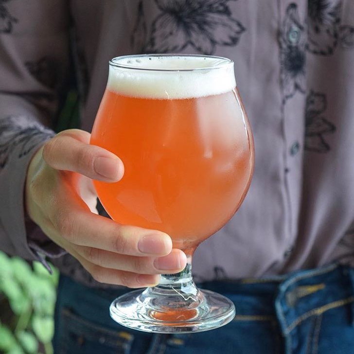 Closeup of person holding chalice of amber-colored beer. Photo by Instagram user @hermitagebrewingsj