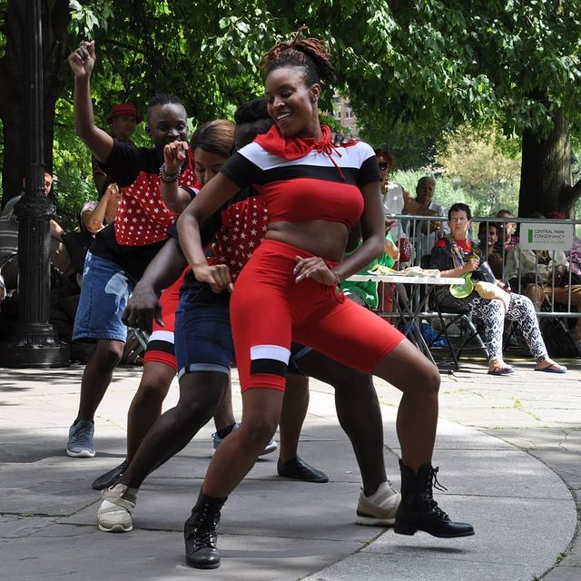 Four dancers in red performing in Central Park. Photo by Instagram user @trish_mayo