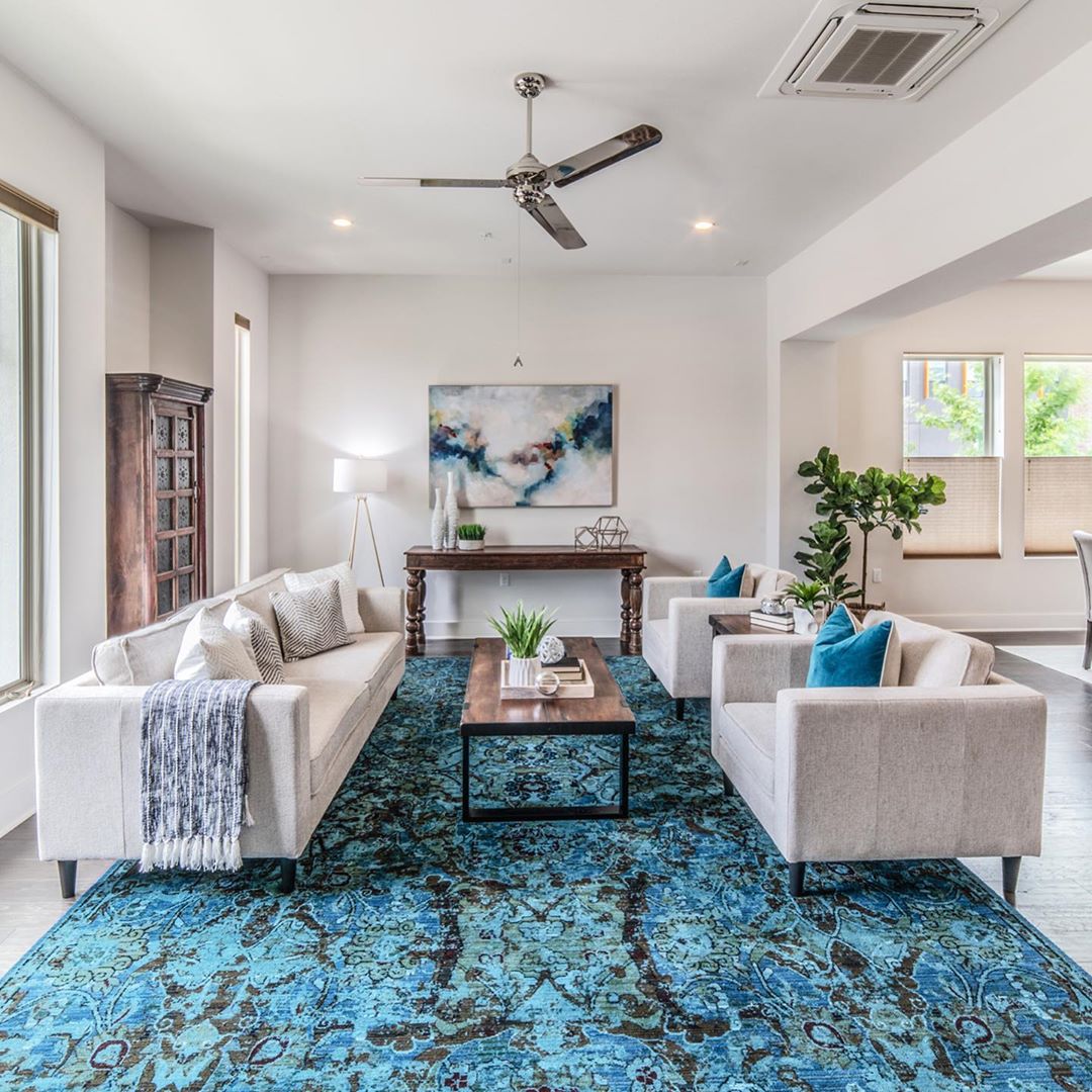 Contemporary living room with white walls and blue accent decor. Photo by Instagram user @debuthomes