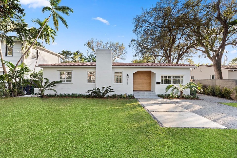 White single-story home on green lawn in the Coconut Grove neighborhood of Miami