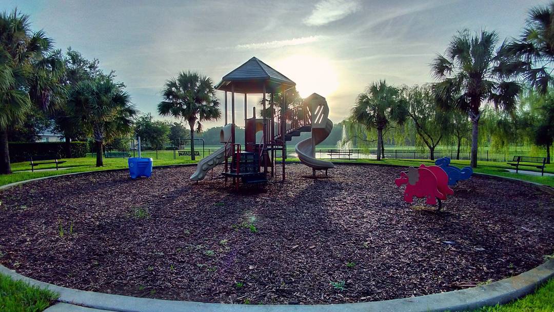 A playground sits in the middle of a park with sunrise in the background. Photo by instagram user @marcelcampos