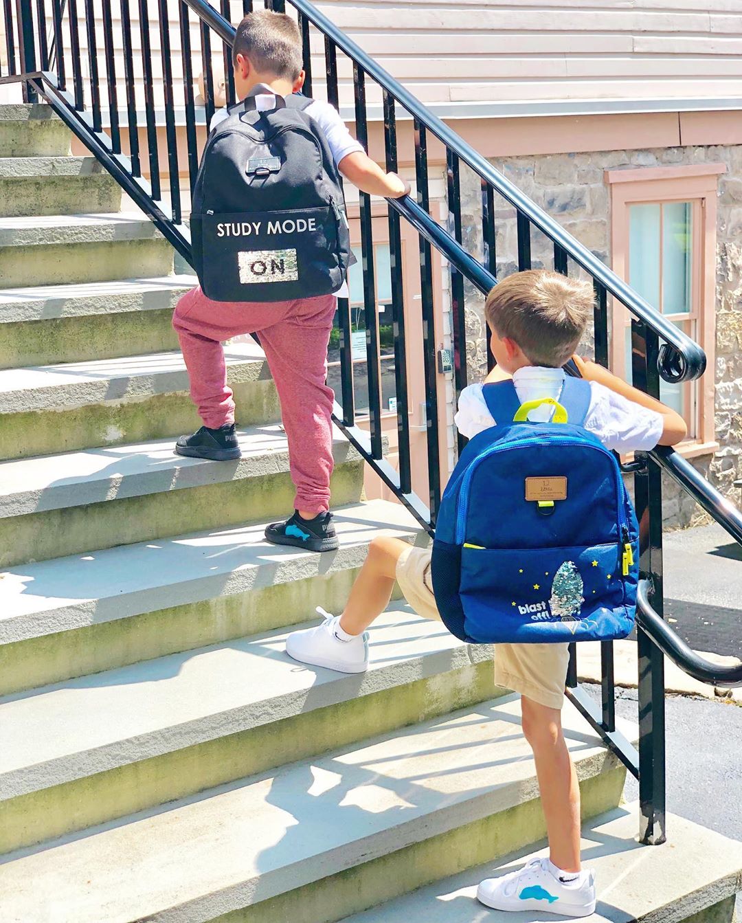 Little boys wearing backpacks climbing school stairs. Photo by Instagram user @twelvelittle
