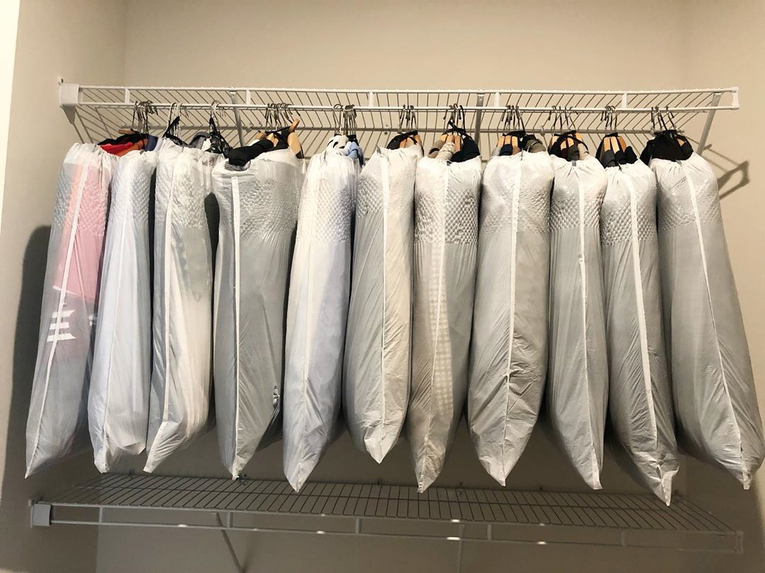 Hangers with clothing covered in garbage bags. Photo by Instagram user @greendoorandmore