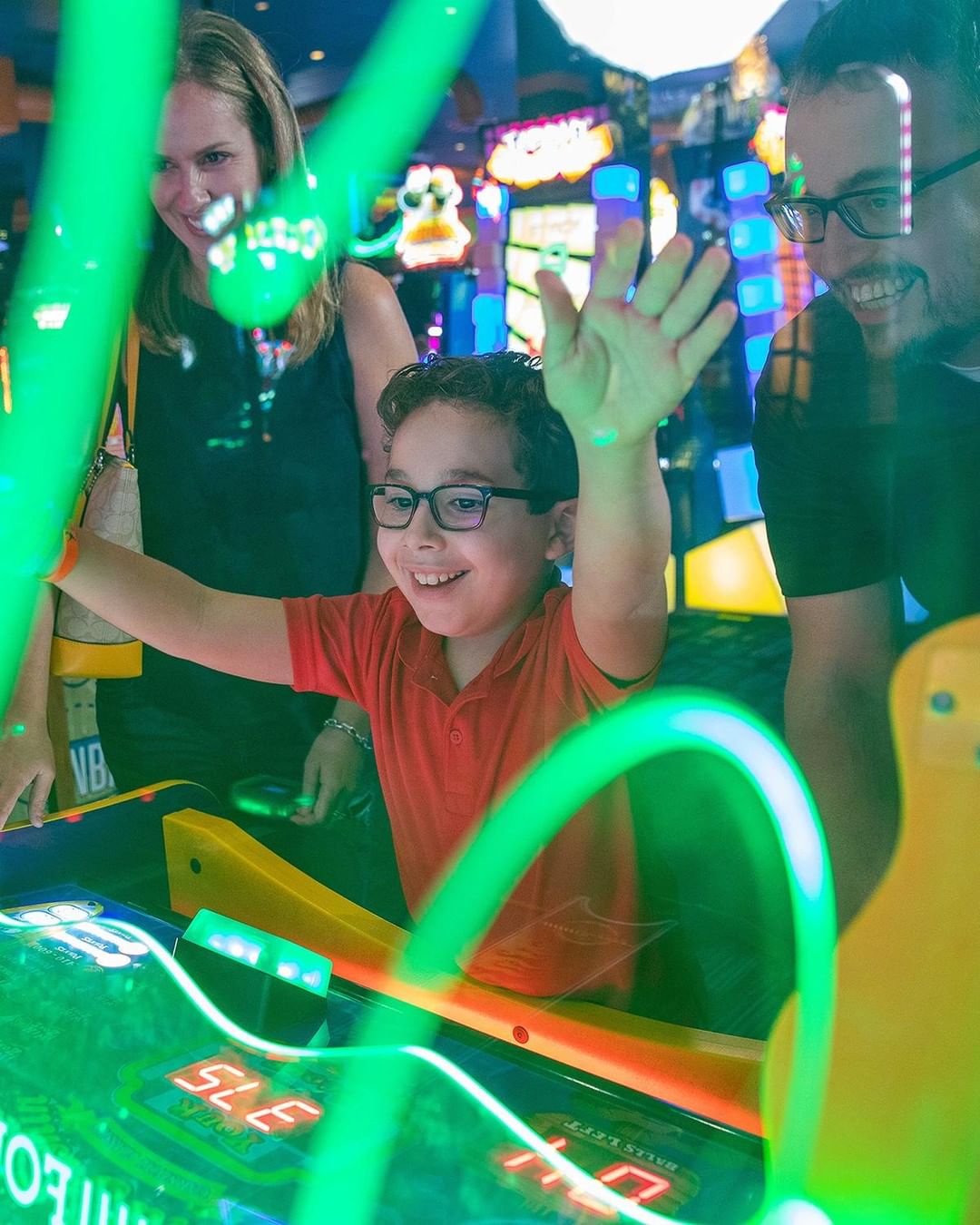 Little boy with parents playing at Dave & Buster's. Photo by Instagram user @daveandbusters