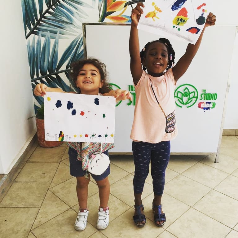 Little girls holding up paintings at The Studio. Photo by Instagram user @thestudiokids_online