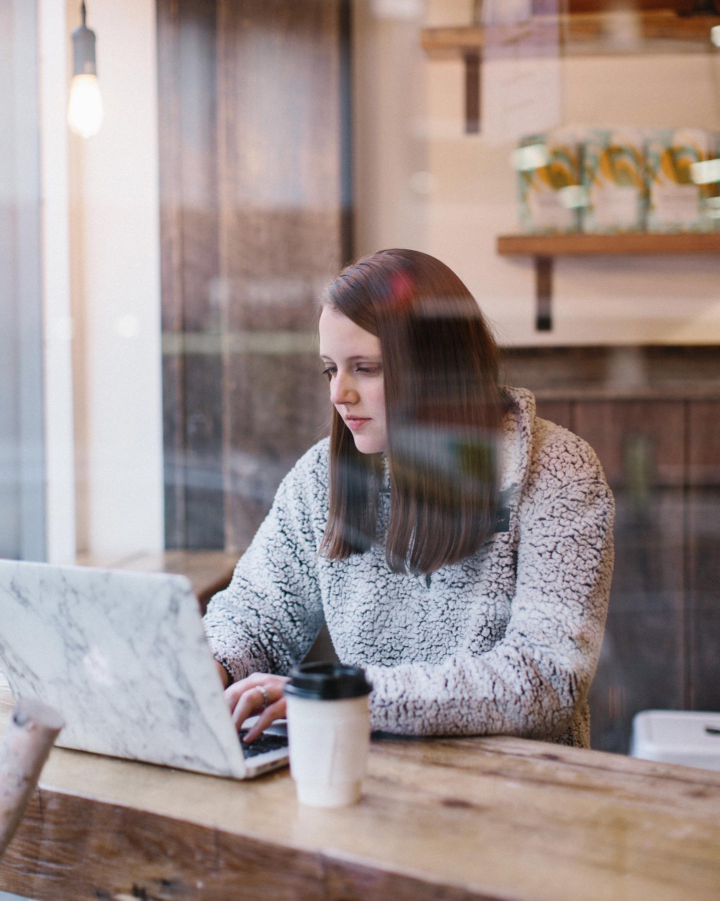 Woman working on laptop in coffee shop. Photo by Instagram user @rachelslifewithlittles