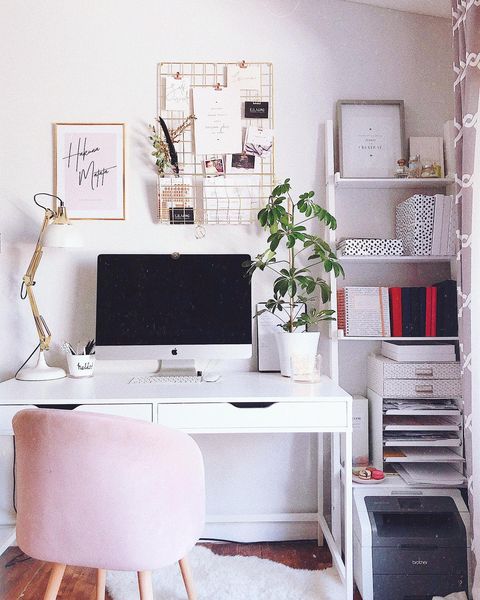 Front view of a office set up with a computer, desk, and comfy pink chair.