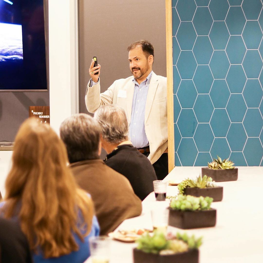 Man standing in front of people giving presentation. Photo by Instagram user @the.skyfactory