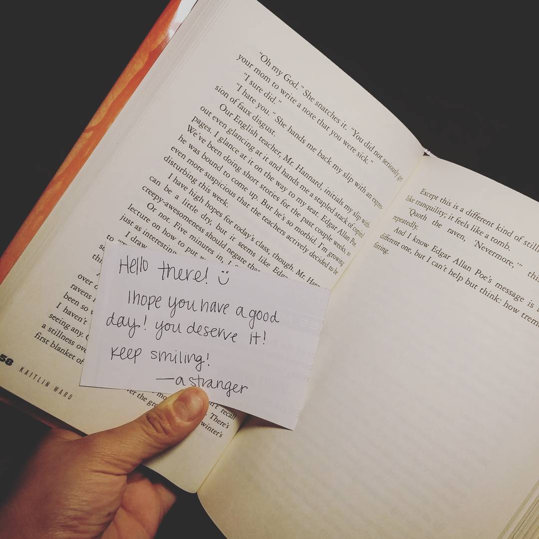 Hand holding book with paper note inside. Photo by Instagram user @scampneoroxy