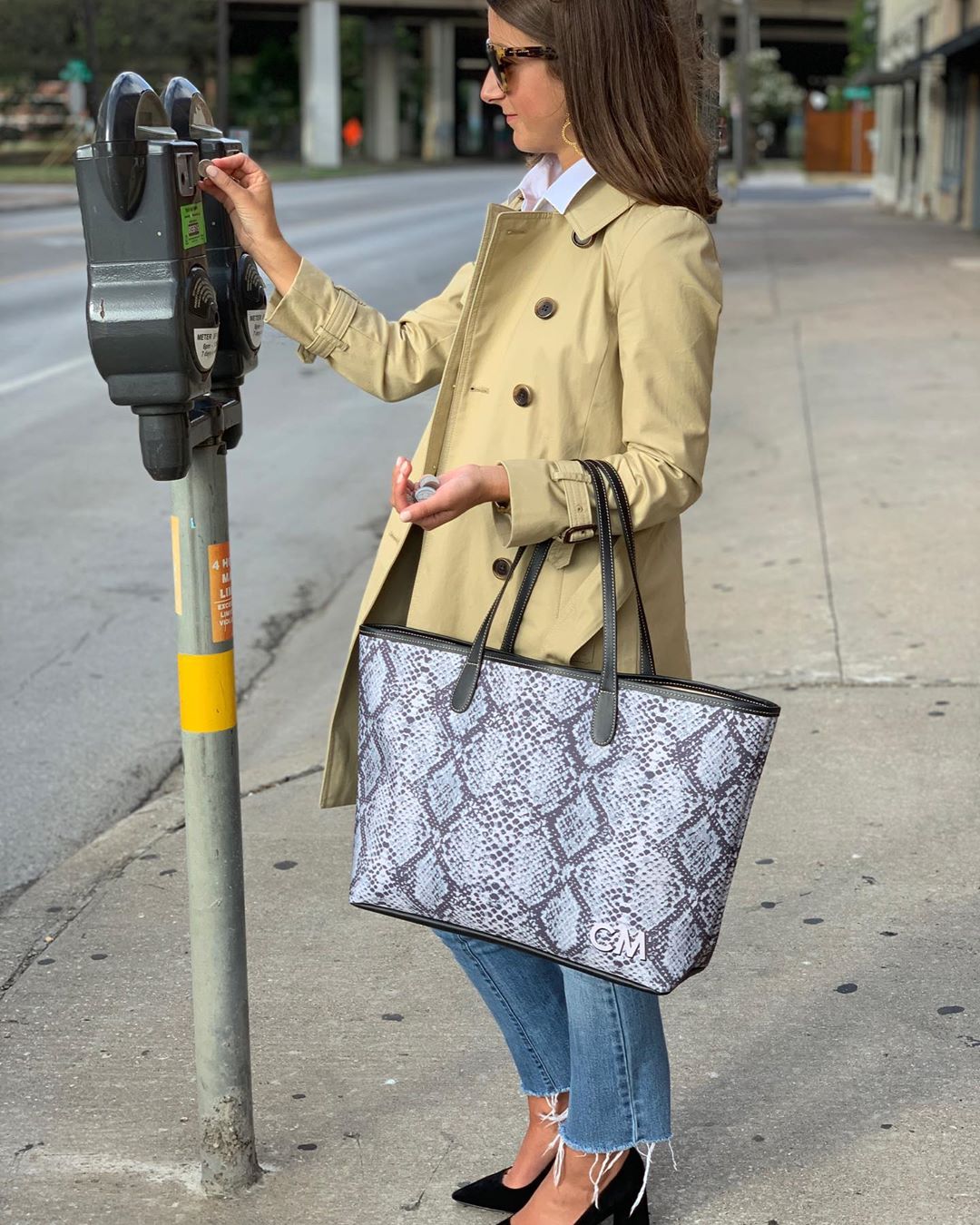 Woman in tan coat putting money in parking meter. Photo by Instagram user @barringtongifts
