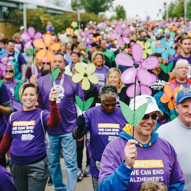 People wearing purple and holding paper flowers. Photo by Instagram user @cvillefit