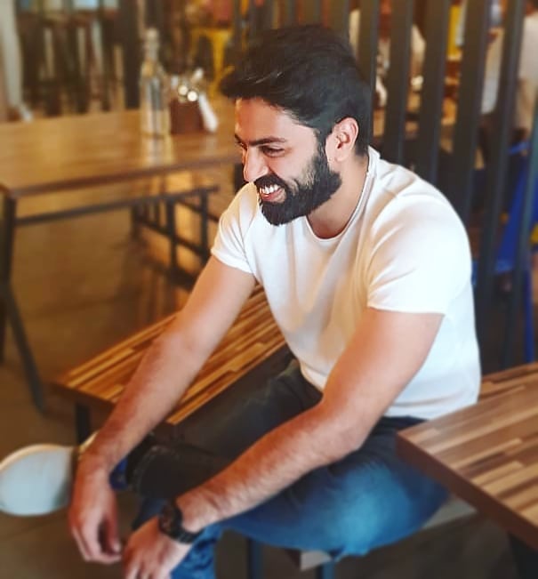 Man sitting on bench inside smiling. Photo by Instagram user @padmasoorya