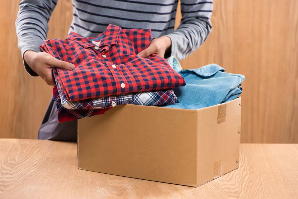 Man filling donation box with clothing