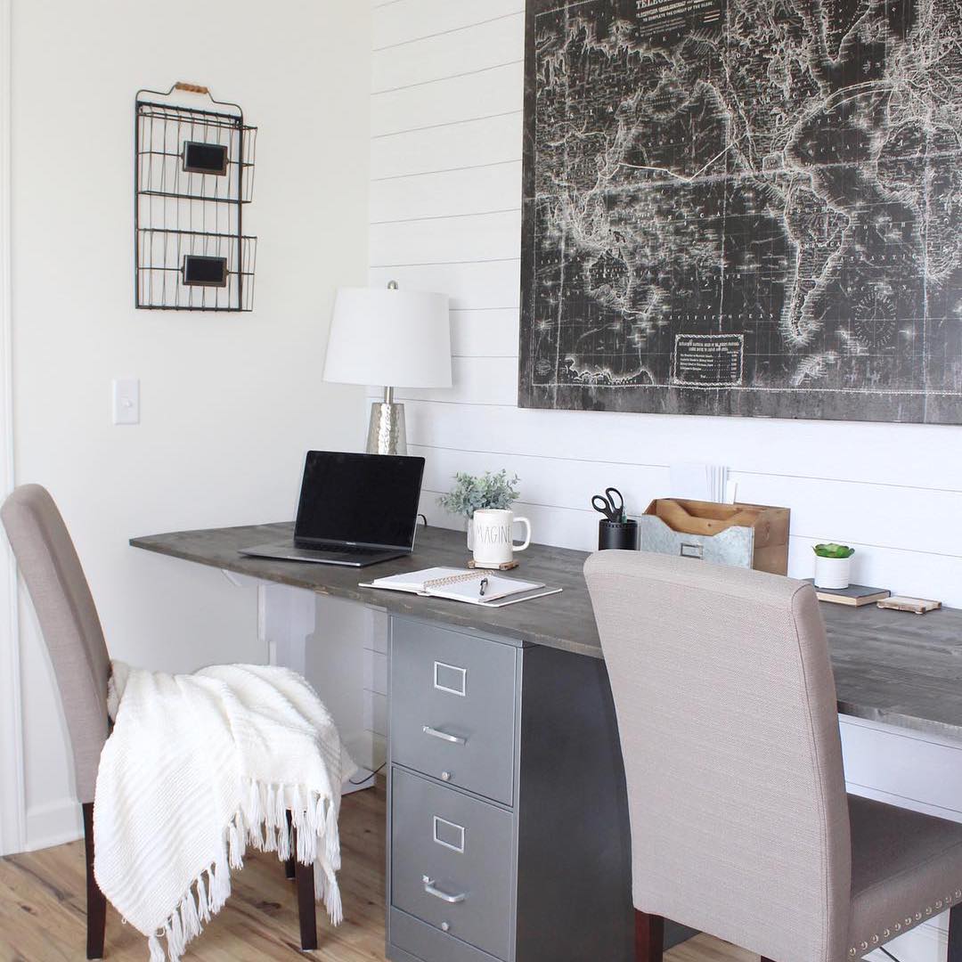 dark home desk with two chairs in front and map on the wall photo by Instagram user @theholtzhouse
