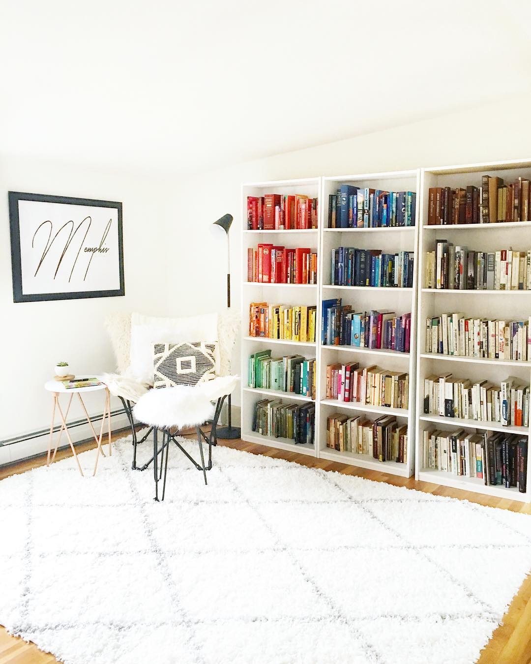 minimalist home library with colorful books and white furniture photo by Instagram user @wonderlandonalice