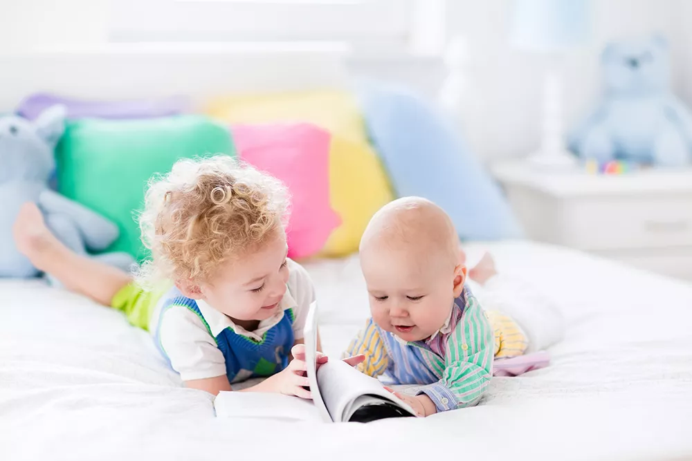 toddler reading to baby