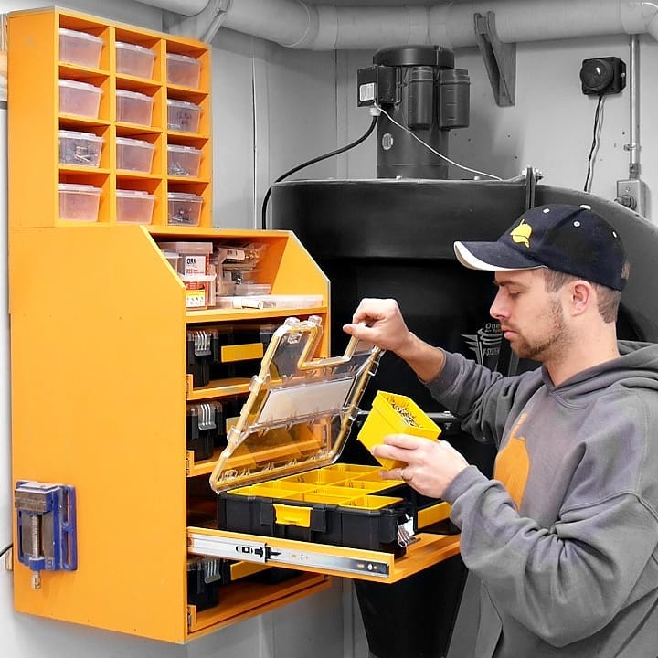 Man putting a small storage cube filled with screws into a storage cabinet. @diytylerg