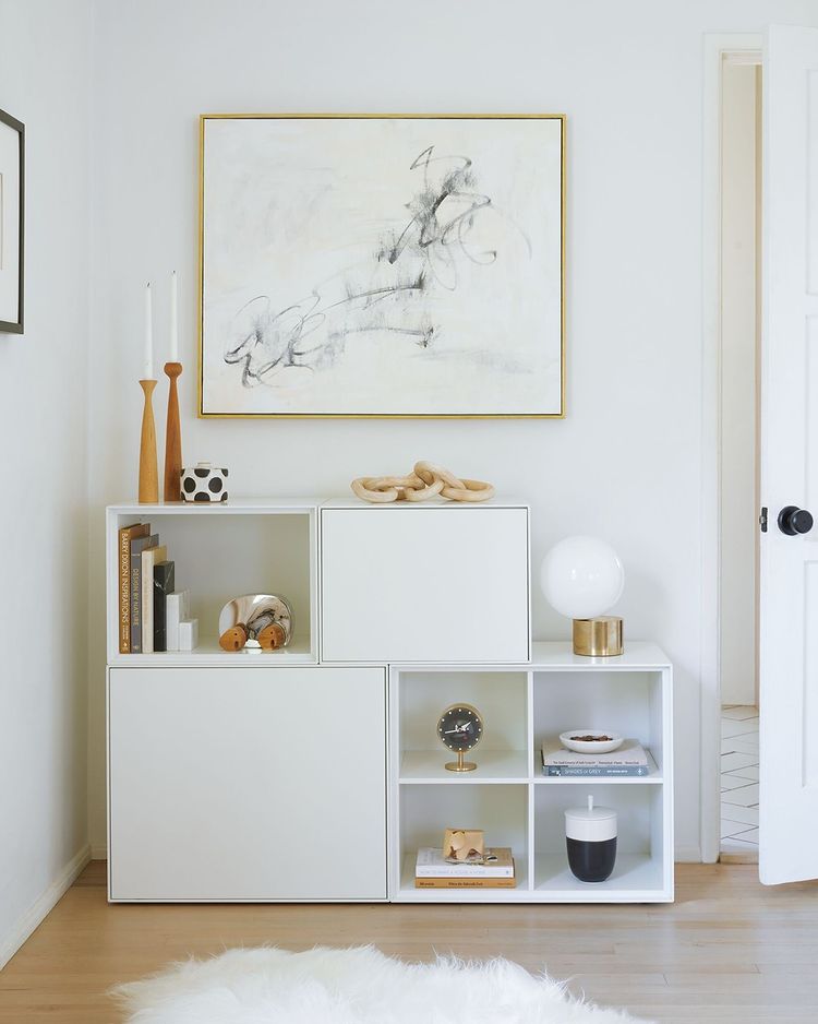 White stacked shelves with indoor decor and a painting above. Photo by Instagram user @designwithinreach