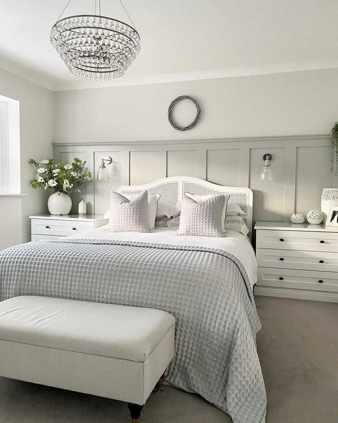 White and cream bedroom with gray bedding and off-white storage bench. Photo by Instagram user @my.millennium.maison