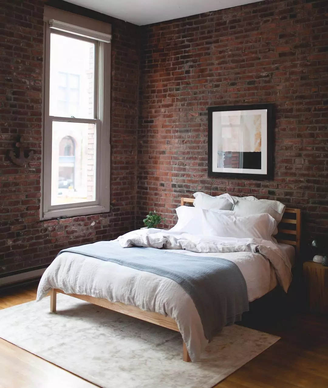 Bed with White Sheets in Brick Bedroom. Photo by Instagram user @jojotastic