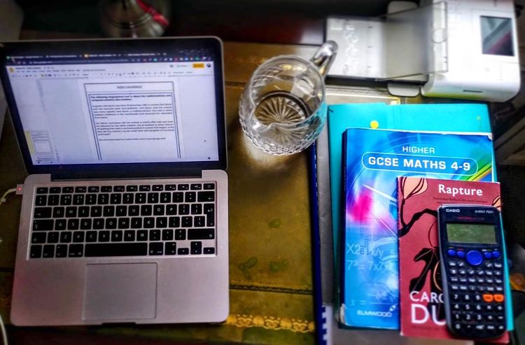 A laptop and books laying on a table. Photo by Instagram user @redbridgetuition