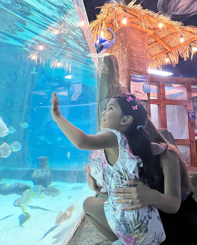 A little child putting her hand agaisnt the wall of the glass aquarium. @seaquestlittleton