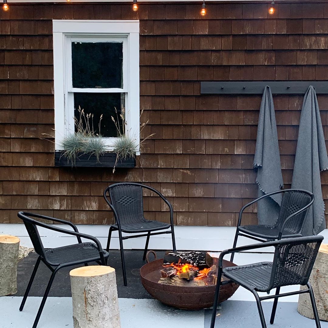 four chairs surrounding a small firepit with logs as side tables for minimalist design photo by Instagram user @most_lovely_things
