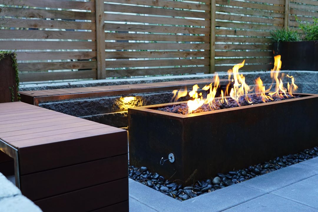 fire pit table in front of bench seating in backyard photo by Instagram user @truescapedesign