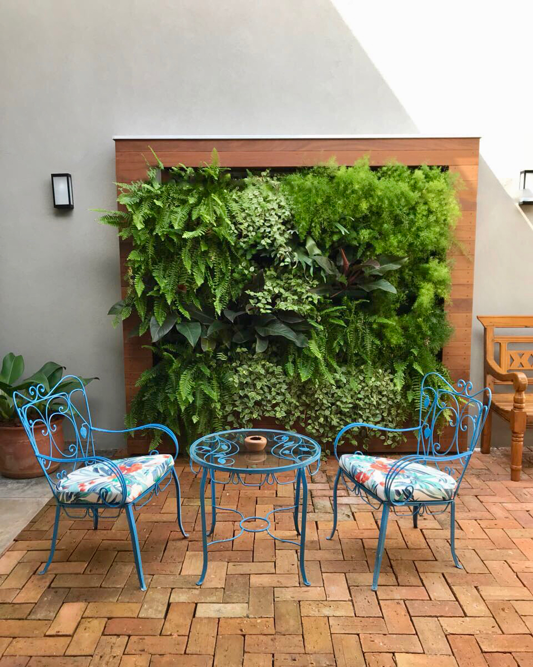 vertical garden wall behind a small bistro set of chairs and a table photo by Instagram user @nogueiraecamillo.arq