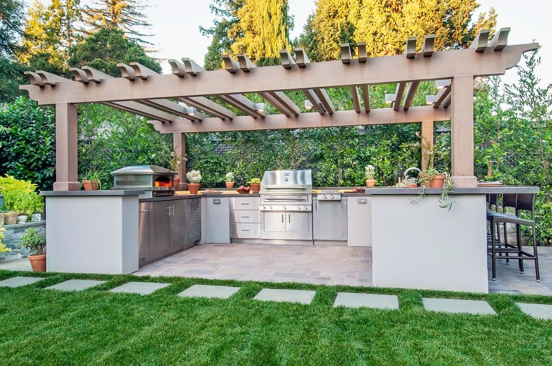 outdoor kitchen built under pergola for shade photo by Instagram user @kalamazoogrills