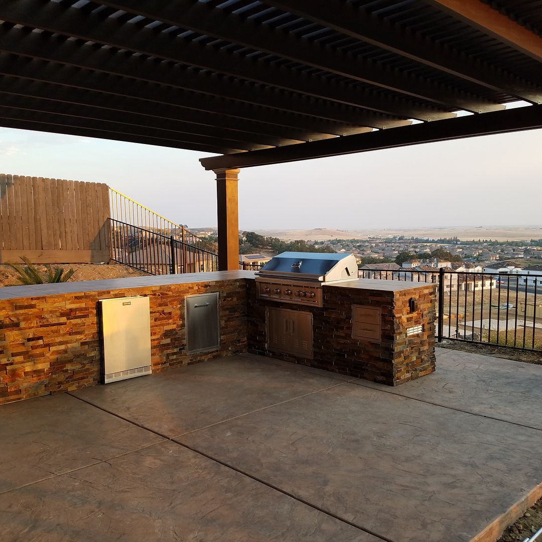 outdoor kitchen with grill built under covered deck photo by Instagram user @sunstonegrills