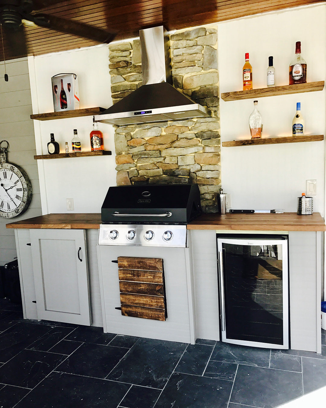 floating shelves with alcohol bottles on top in outdoor kitchen photo by Instagram user @w3tbak_ 