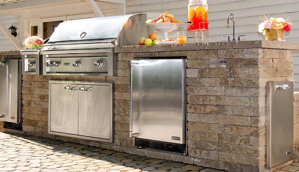 Outdoor kitchen built using a full outdoor kitchen kit with grill, fridge, and sink photo by Instagram user @prestigebrickandstone