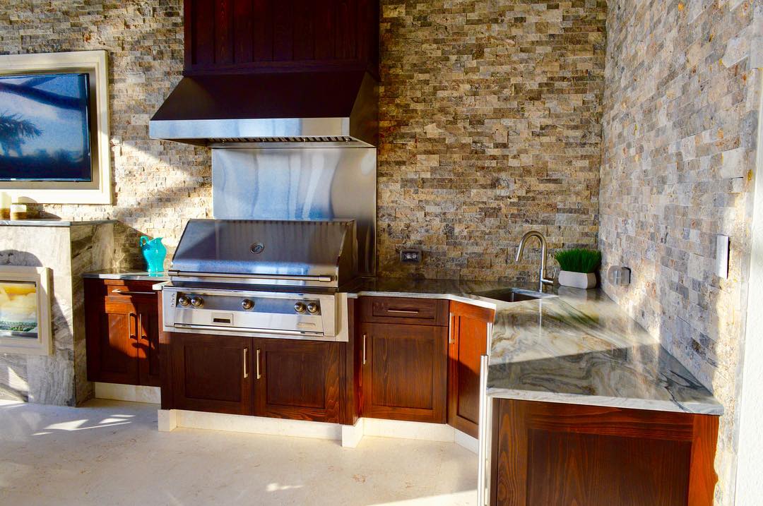 outdoor kitchen with sink and grill that has a hood installed overhead photo by Instagram user @edswflrealtor