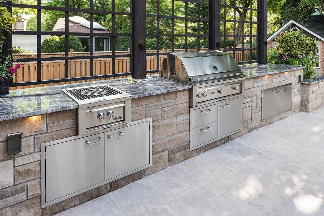 outdoor kitchen area with stove top and grill with built in warming drawers photo by Instagram user @lynxgrills
