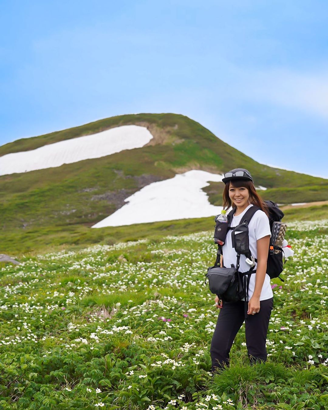 Woman with Backpack and Photography Equipment Hiking Through Green Hills. Photo by Instagram user @yumika0121