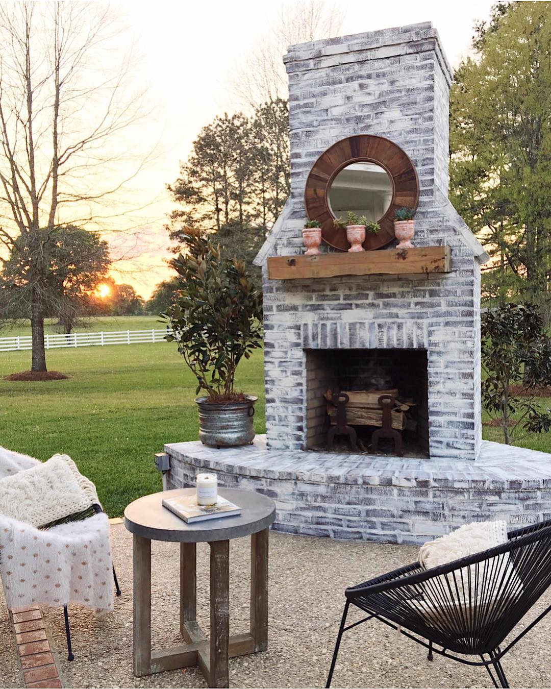 outdoor fireplace installed in the backyard with seating in front photo by Instagram user @cindimc.ivoryhomedesign