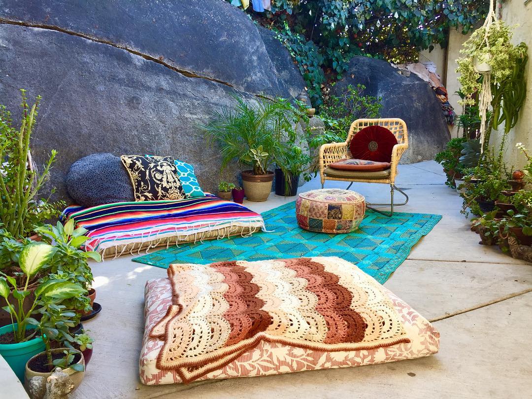 blankets and pillows placed on the floor outdoors to make more room in a small backyard photo by Instagram user @lil._.bird