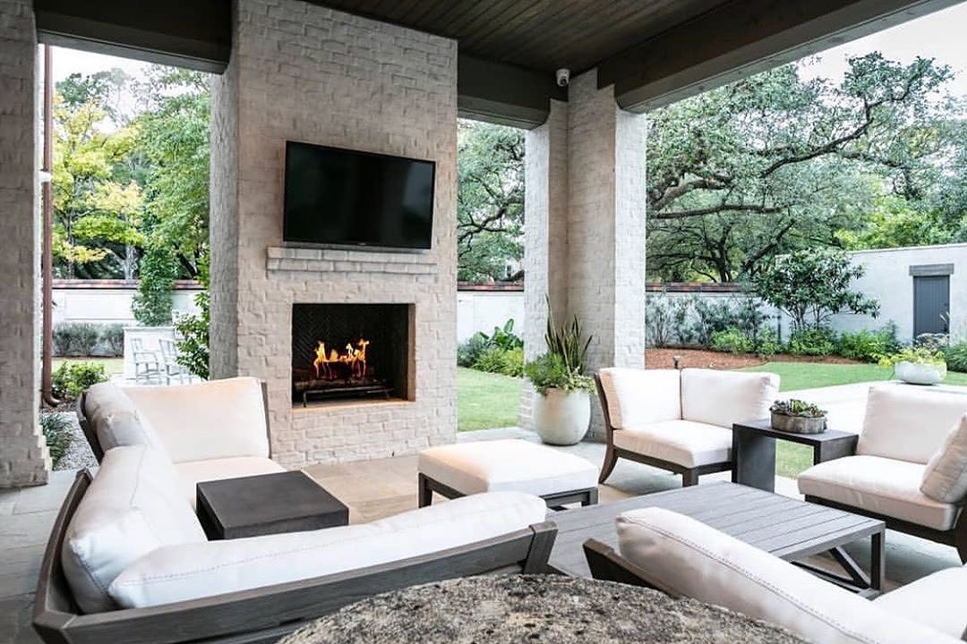 outdoor TV installed on outdoor fireplace with furniture all around photo by Instagram user @patioproductsusa