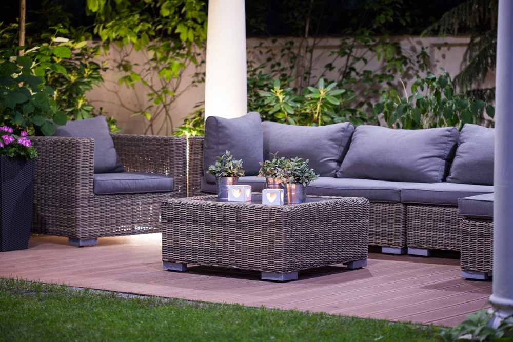 Wicker patio furniture set with blue cushions and a coffee table at dusk