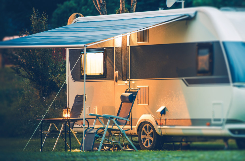 RV camper at night with chairs under canopy