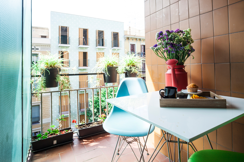A small balcony with a table, chair, and plant decorations