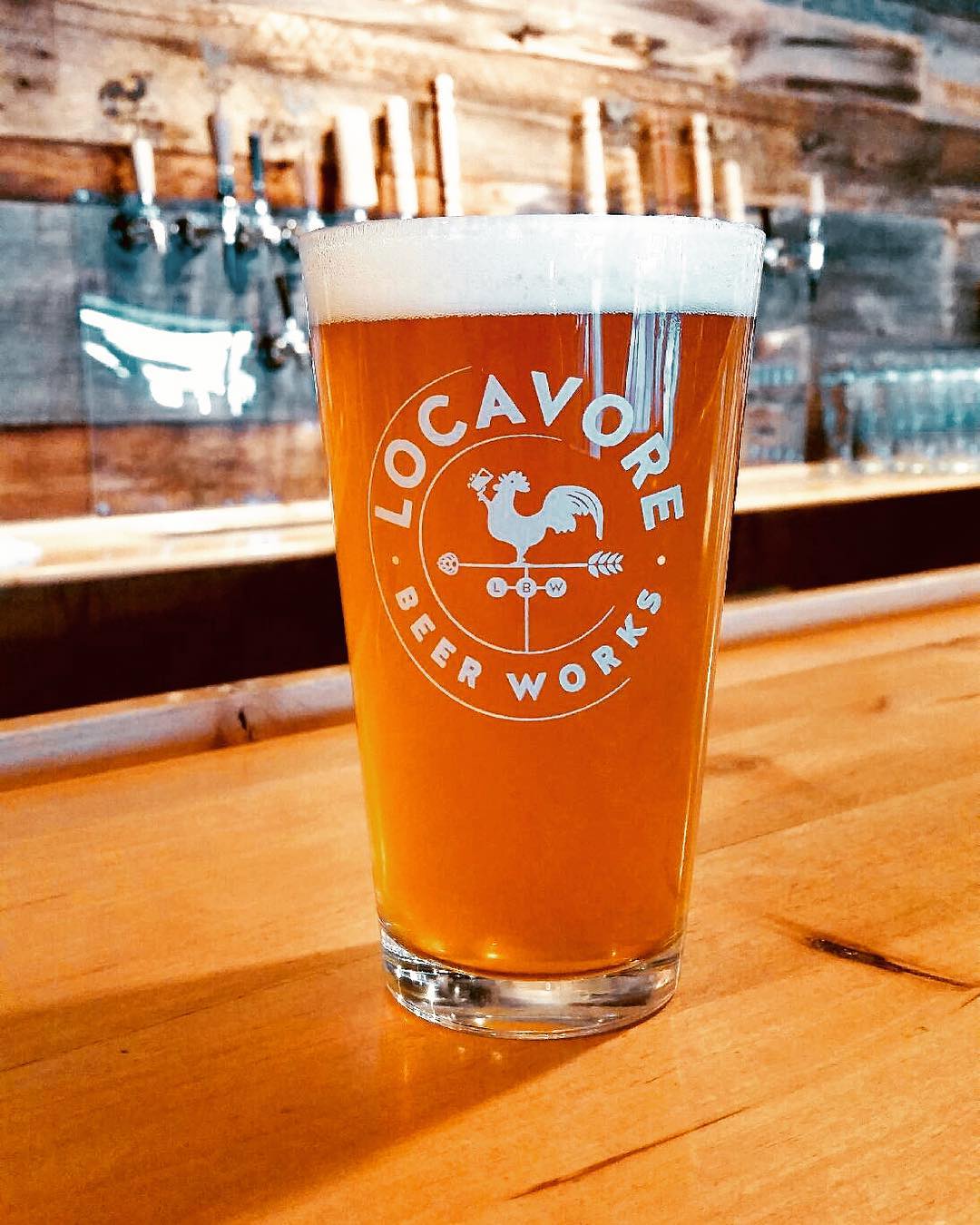 Closeup of amber-colored beer in a pint grass sitting on a bat with taps in the background Photo by Instagram user @locavorebeerworks