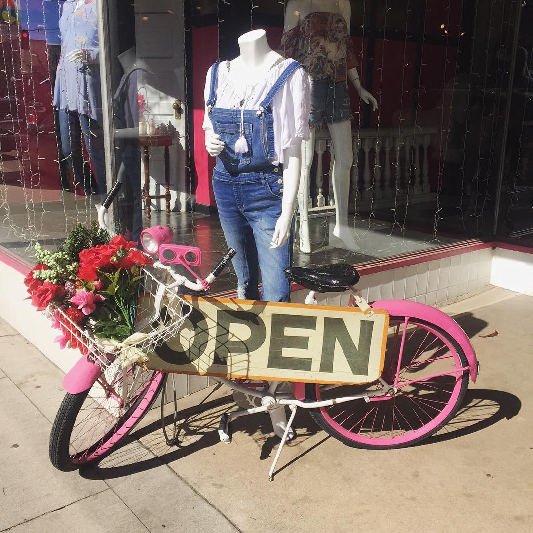 Front of boutique with mannequin and pink bicycle in front with an open sign Photo by Instagram user @detailsboutique