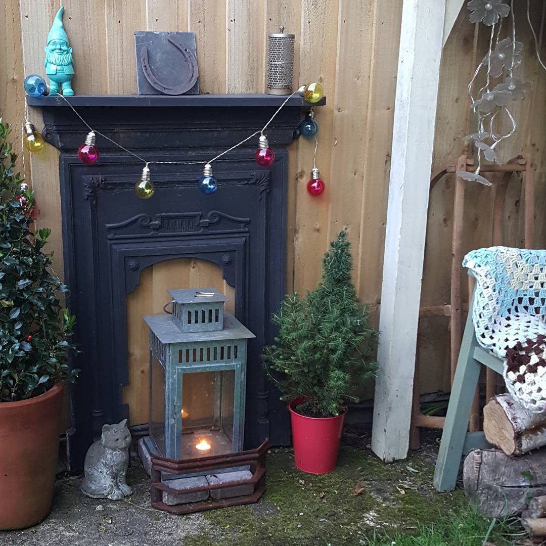 small fake fireplace outside with lantern on the ground photo by Instagram user @katysclutter