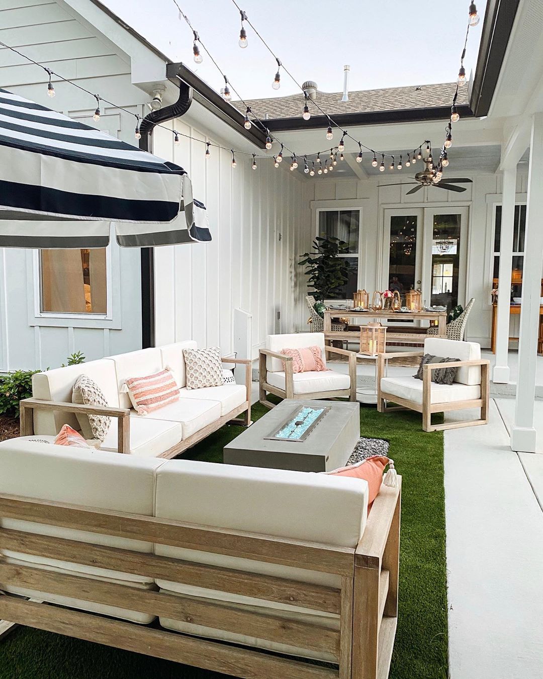 outdoor living area with seating and a fire table with string lights overhead photo by Instagram user @hauteofftherack